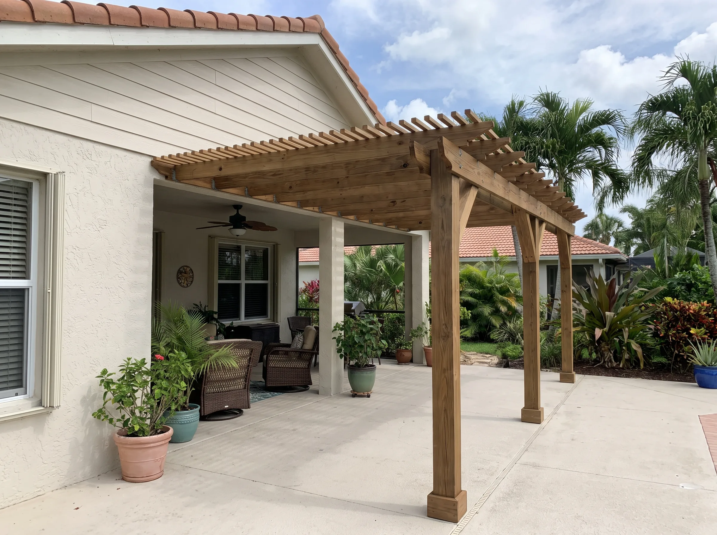 Attached pergola ledger-mounted to a single-story Florida house wall over the patio.